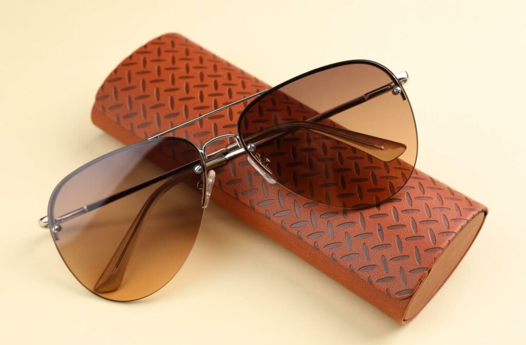 A pair of aviator sunglasses resting on a brown leather case.