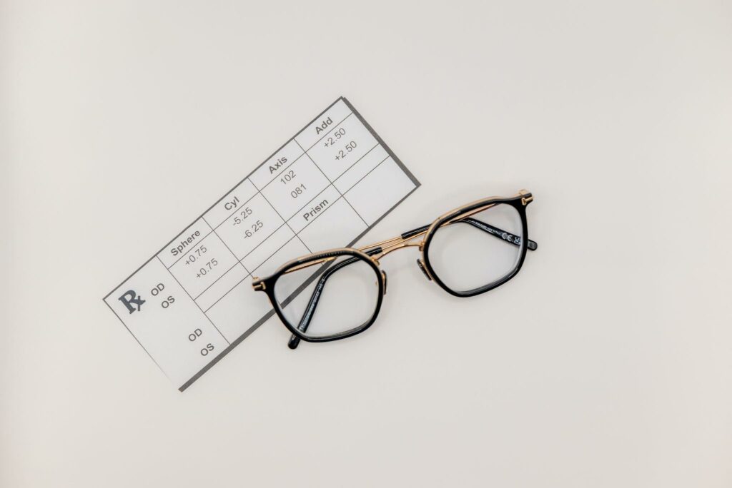 Folded eyeglasses with round dark metal frames and tortoiseshell temples resting on a surface.