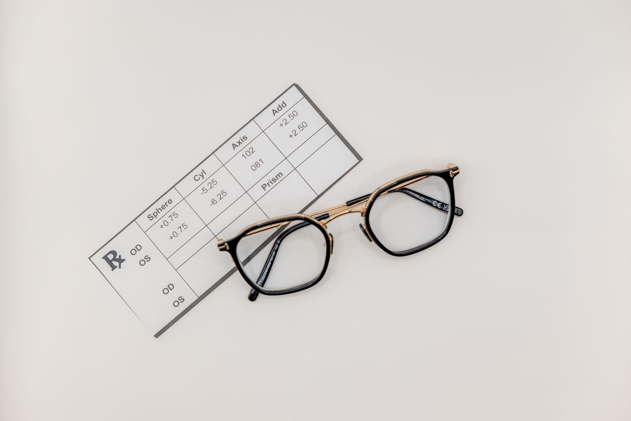 Folded eyeglasses with round dark metal frames and tortoiseshell temples resting on a surface.